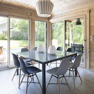 La salle à manger lumineuse de cette maison bois s'ouvre sur la terrasse avec piscine