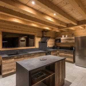 Une cuisine moderne et ouverte en bois et noir dans un chalet de montagne